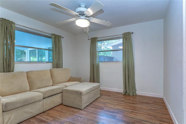 living room featuring ceiling fan, light hardwood / wood-style floors, and a wealth of natural light