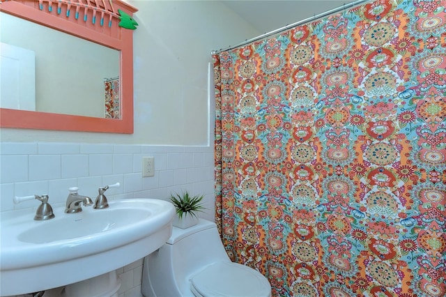 bathroom featuring backsplash, tile walls, toilet, and sink