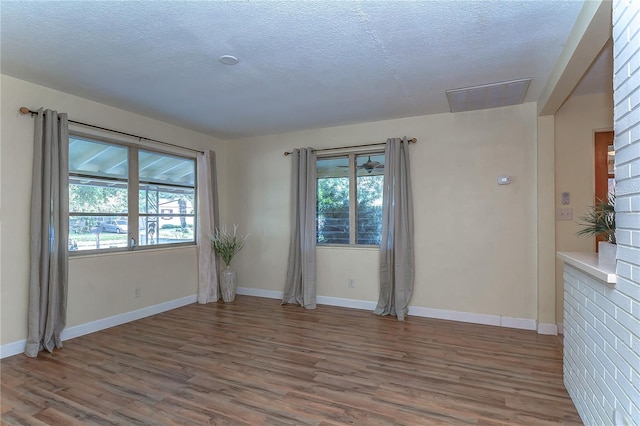 empty room with a textured ceiling and hardwood / wood-style flooring