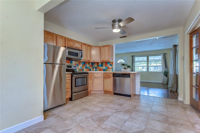 kitchen featuring ceiling fan, light wood-type flooring, light brown cabinets, decorative backsplash, and appliances with stainless steel finishes