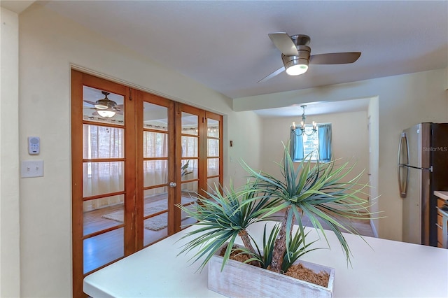 dining area with ceiling fan with notable chandelier, a healthy amount of sunlight, hardwood / wood-style flooring, and french doors