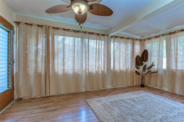 interior space with plenty of natural light, ceiling fan, hardwood / wood-style floors, and beamed ceiling