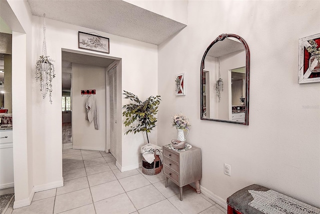 corridor featuring a textured ceiling and light tile patterned flooring