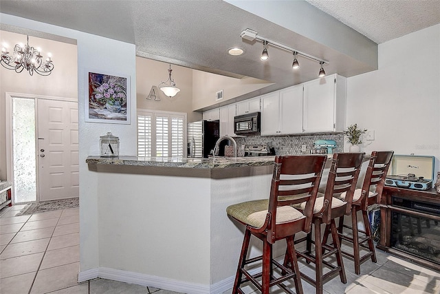 kitchen featuring rail lighting, white cabinets, light tile patterned floors, decorative light fixtures, and stainless steel fridge with ice dispenser