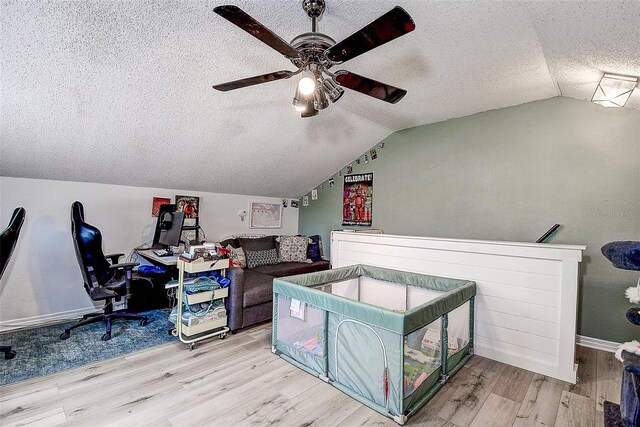 office space featuring ceiling fan, a textured ceiling, light hardwood / wood-style flooring, and lofted ceiling