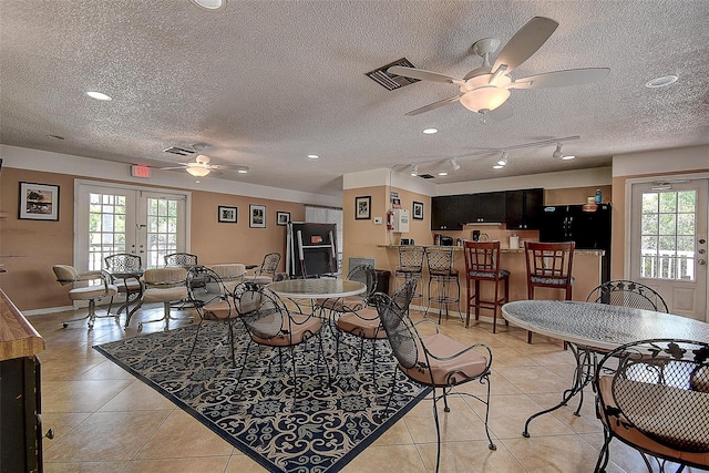 tiled living room featuring a textured ceiling, ceiling fan, track lighting, and french doors