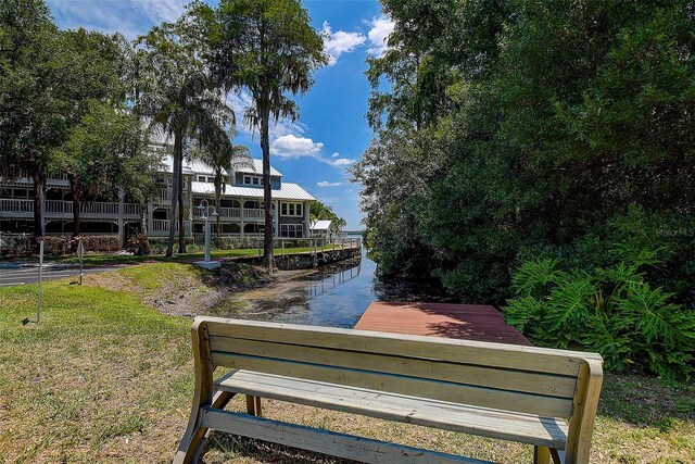 view of property's community featuring a lawn and a dock