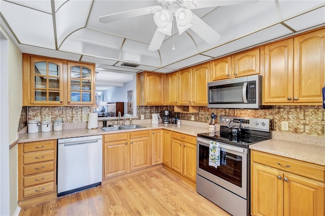 kitchen featuring ceiling fan, decorative backsplash, light hardwood / wood-style floors, sink, and stainless steel appliances