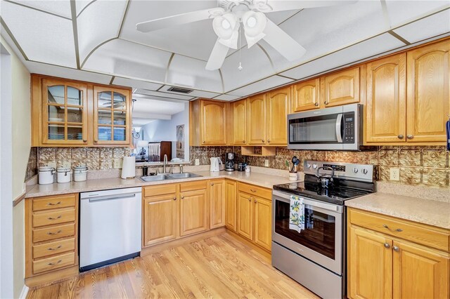 19029 US Highway 19 N Unit 12B, Clearwater, FL 33764 - kitchen featuring stainless steel appliances, a sink, light wood-style flooring, decorative backsplash, and light countertops