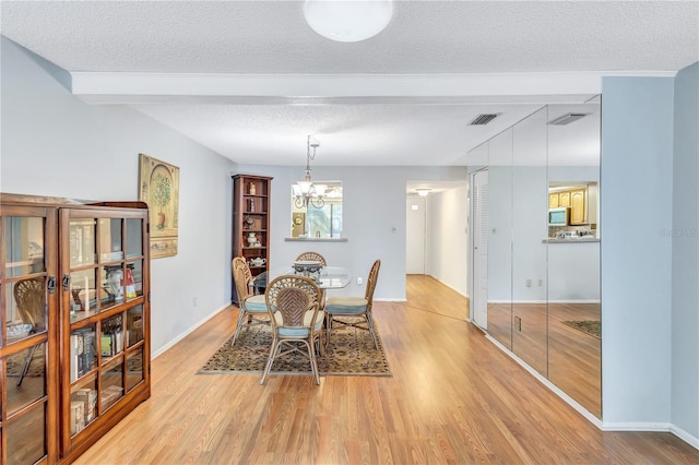 dining area featuring an inviting chandelier, a textured ceiling, and light hardwood / wood-style flooring