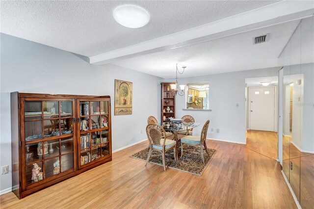 19029 US Highway 19 N Unit 12B, Clearwater, FL 33764 - dining space featuring a textured ceiling, beamed ceiling, light wood-style flooring, a chandelier, and baseboards