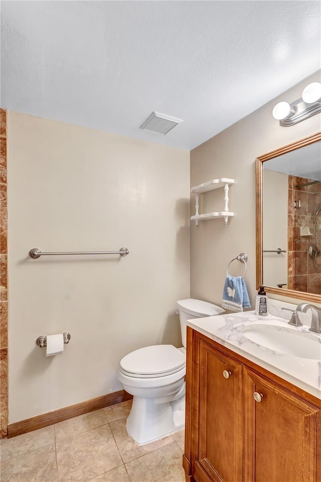 bathroom with tile patterned flooring, toilet, a textured ceiling, and vanity