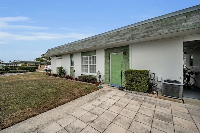 property entrance with central AC unit and a yard