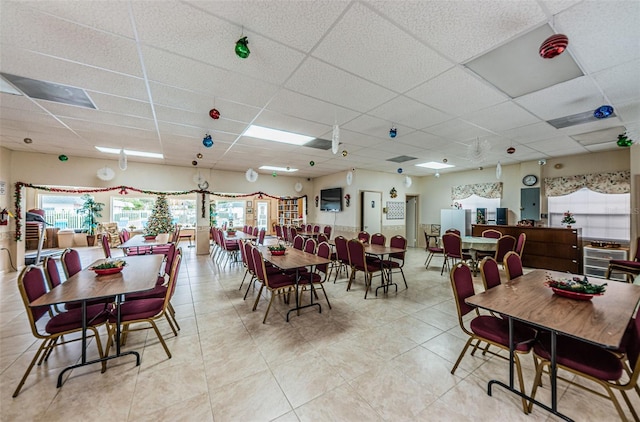 dining room featuring light tile patterned floors and a drop ceiling