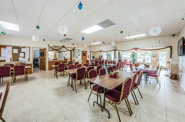 dining room with light tile patterned floors and a drop ceiling