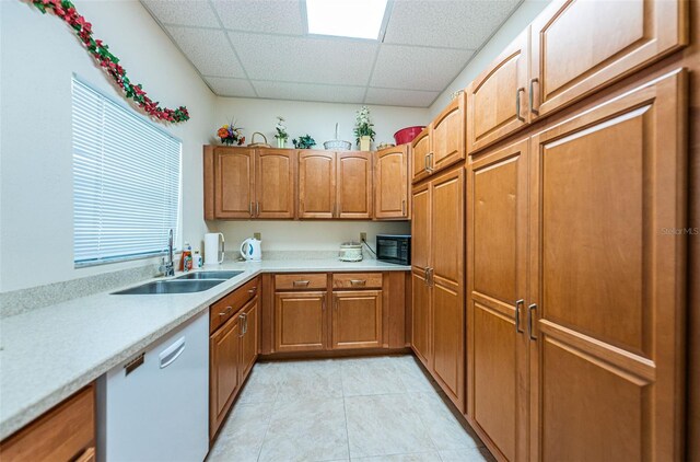 kitchen with brown cabinets, light countertops, white dishwasher, a sink, and black microwave