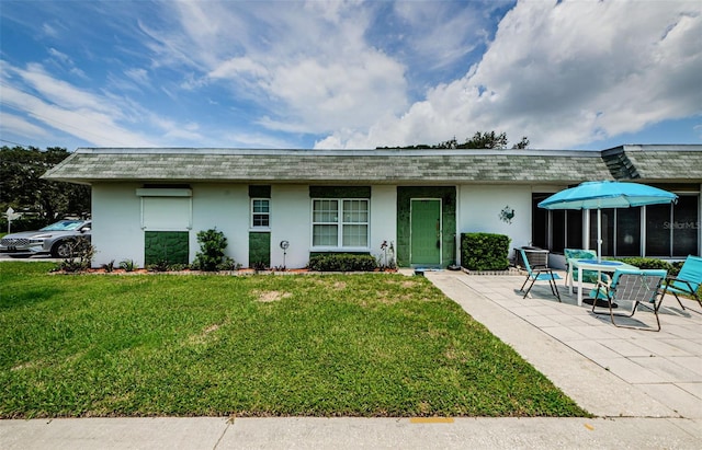 back of property featuring a lawn, a patio area, and stucco siding