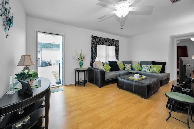 living area with a ceiling fan, baseboards, and light wood finished floors