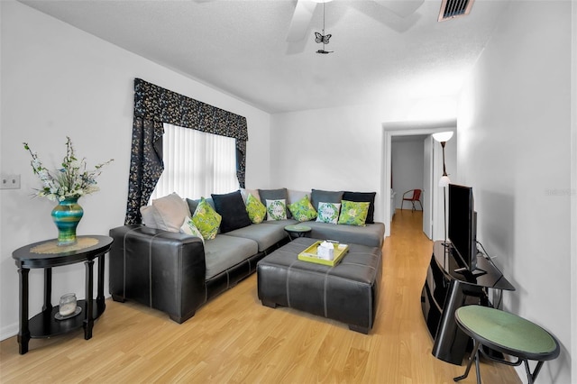 living area with visible vents, ceiling fan, a textured ceiling, and light wood-style flooring