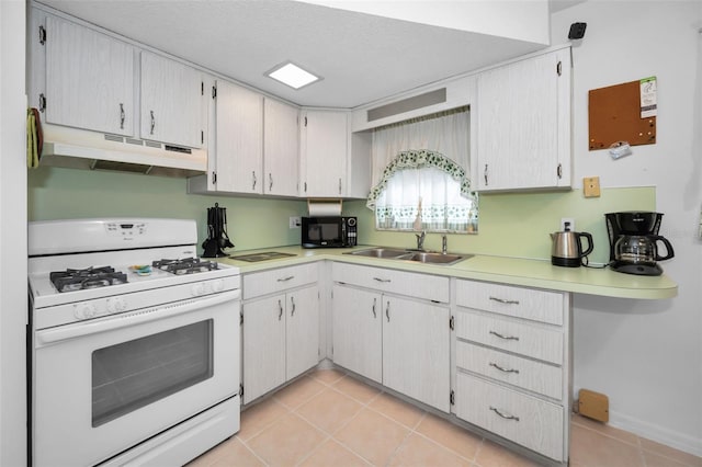 kitchen featuring black microwave, light tile patterned floors, under cabinet range hood, a sink, and gas range gas stove