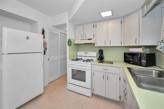 kitchen featuring white appliances, light countertops, under cabinet range hood, a sink, and light tile patterned flooring