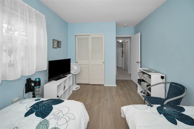 bedroom featuring a closet, a textured ceiling, and wood finished floors