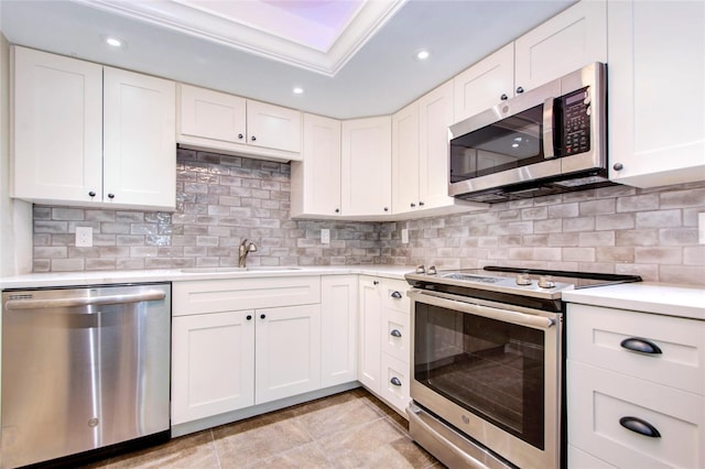 kitchen with appliances with stainless steel finishes, backsplash, white cabinetry, and sink