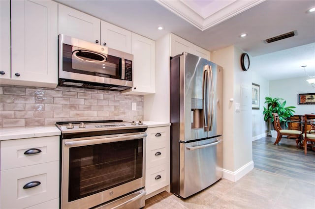 kitchen featuring light hardwood / wood-style flooring, appliances with stainless steel finishes, light stone countertops, white cabinetry, and tasteful backsplash