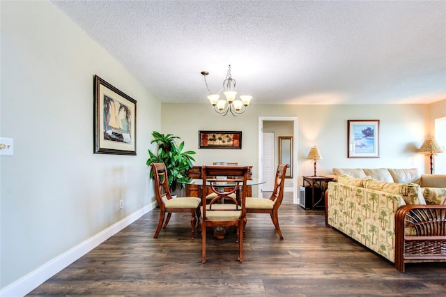 dining space with dark wood-style flooring, a textured ceiling, baseboards, and an inviting chandelier