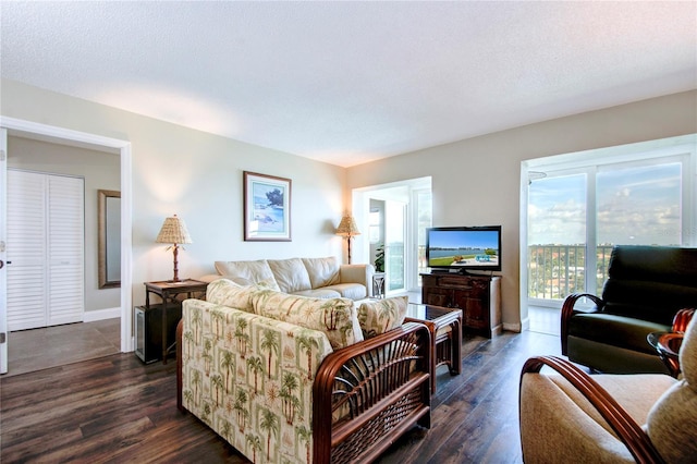 living room with dark wood finished floors, a textured ceiling, and baseboards