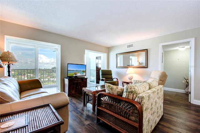 living area with dark wood-style floors, a textured ceiling, visible vents, and baseboards