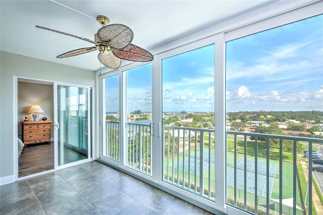 unfurnished sunroom featuring a wealth of natural light, ceiling fan, and a water view