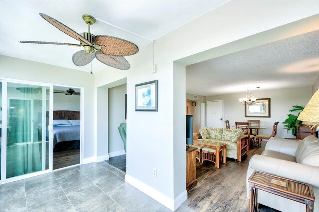 living room featuring ceiling fan with notable chandelier, a textured ceiling, and hardwood / wood-style flooring