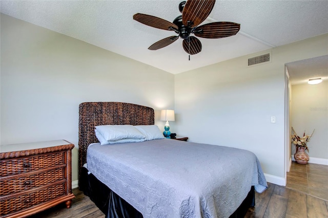 bedroom with ceiling fan, dark hardwood / wood-style flooring, and a textured ceiling