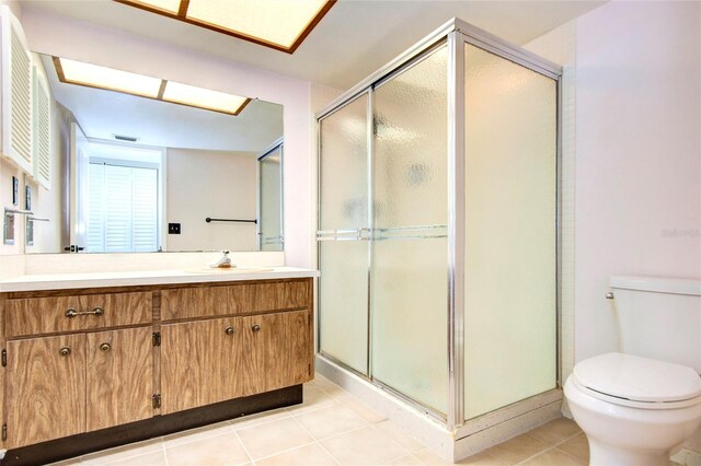 bathroom with tile patterned flooring, walk in shower, toilet, and vanity