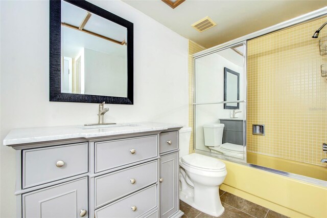 full bathroom with tile patterned floors, shower / bath combination with glass door, toilet, and vanity