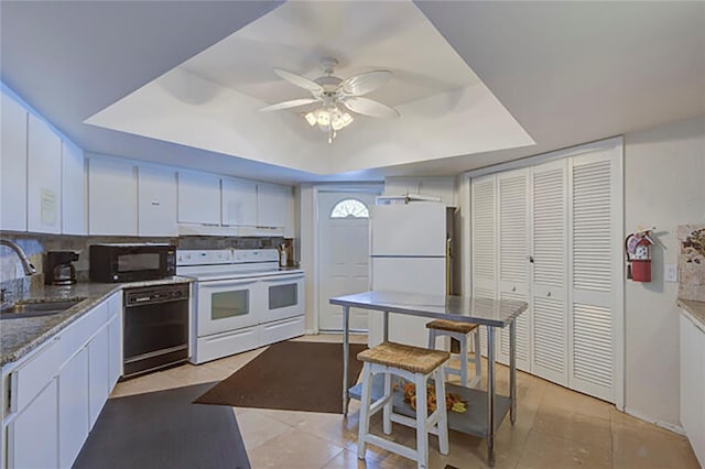 kitchen with under cabinet range hood, a sink, white cabinetry, black appliances, and a raised ceiling