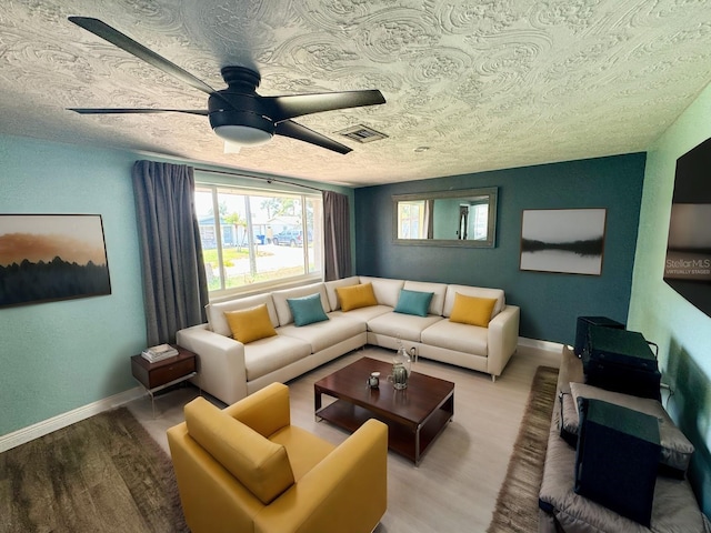 living room featuring ceiling fan, a textured ceiling, and wood-type flooring