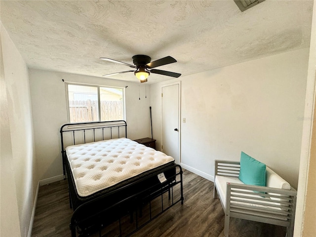 bedroom with ceiling fan, dark wood-type flooring, and a textured ceiling