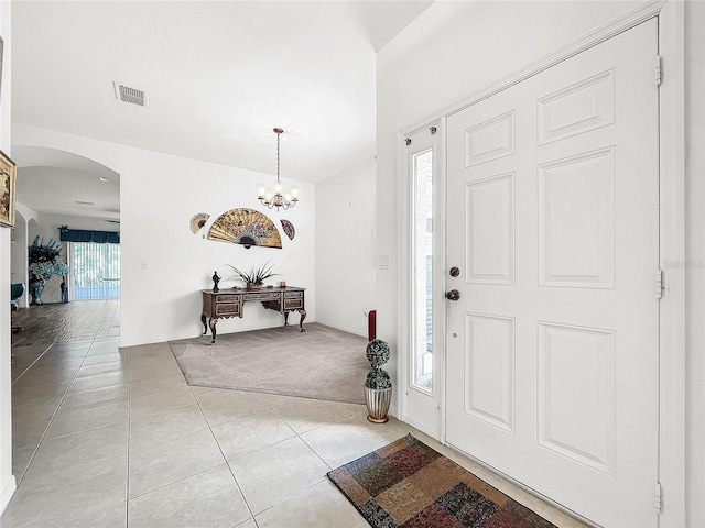 tiled foyer with a notable chandelier