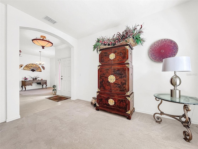 foyer entrance featuring light carpet and a chandelier