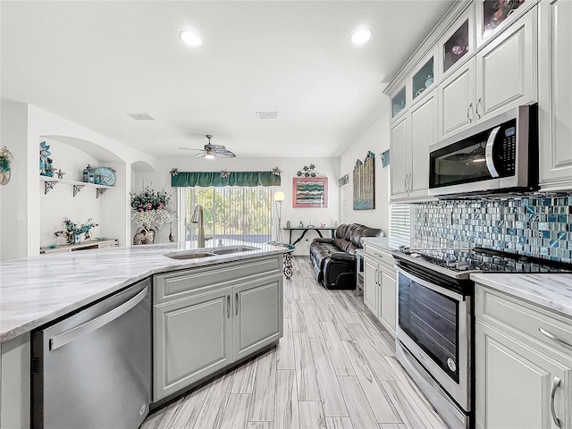 kitchen featuring white cabinetry, ceiling fan, stainless steel appliances, light stone countertops, and sink