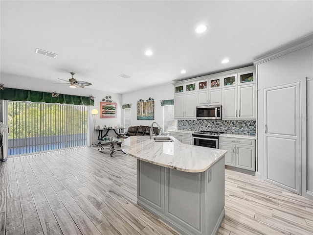 kitchen with white cabinetry, stainless steel appliances, sink, a kitchen island with sink, and ceiling fan