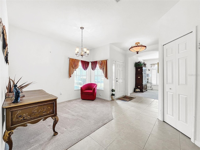 foyer with light carpet and a chandelier