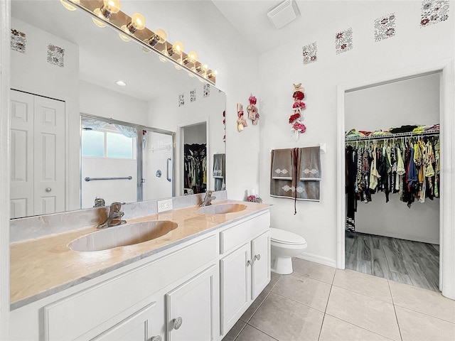 bathroom featuring a shower with shower door, tile patterned floors, vanity, and toilet