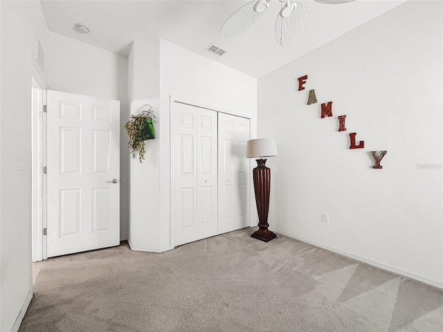 unfurnished bedroom with ceiling fan, a closet, and light carpet