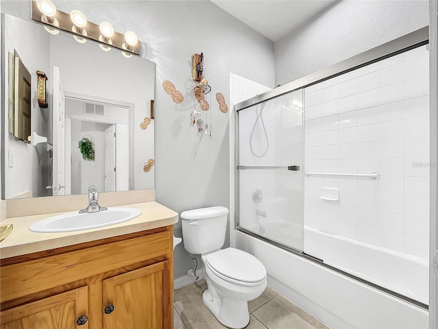 full bathroom featuring toilet, bath / shower combo with glass door, tile patterned flooring, and vanity