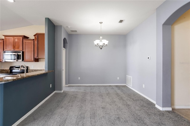 kitchen featuring appliances with stainless steel finishes, a chandelier, vaulted ceiling, hanging light fixtures, and light colored carpet