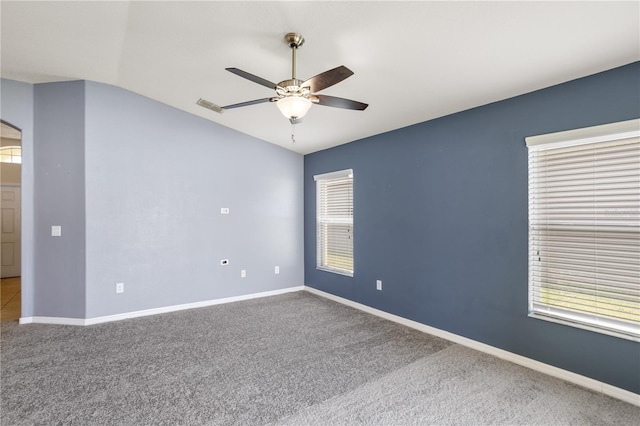 carpeted spare room featuring ceiling fan, vaulted ceiling, and a wealth of natural light