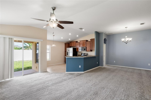 kitchen with appliances with stainless steel finishes, vaulted ceiling, kitchen peninsula, and light colored carpet